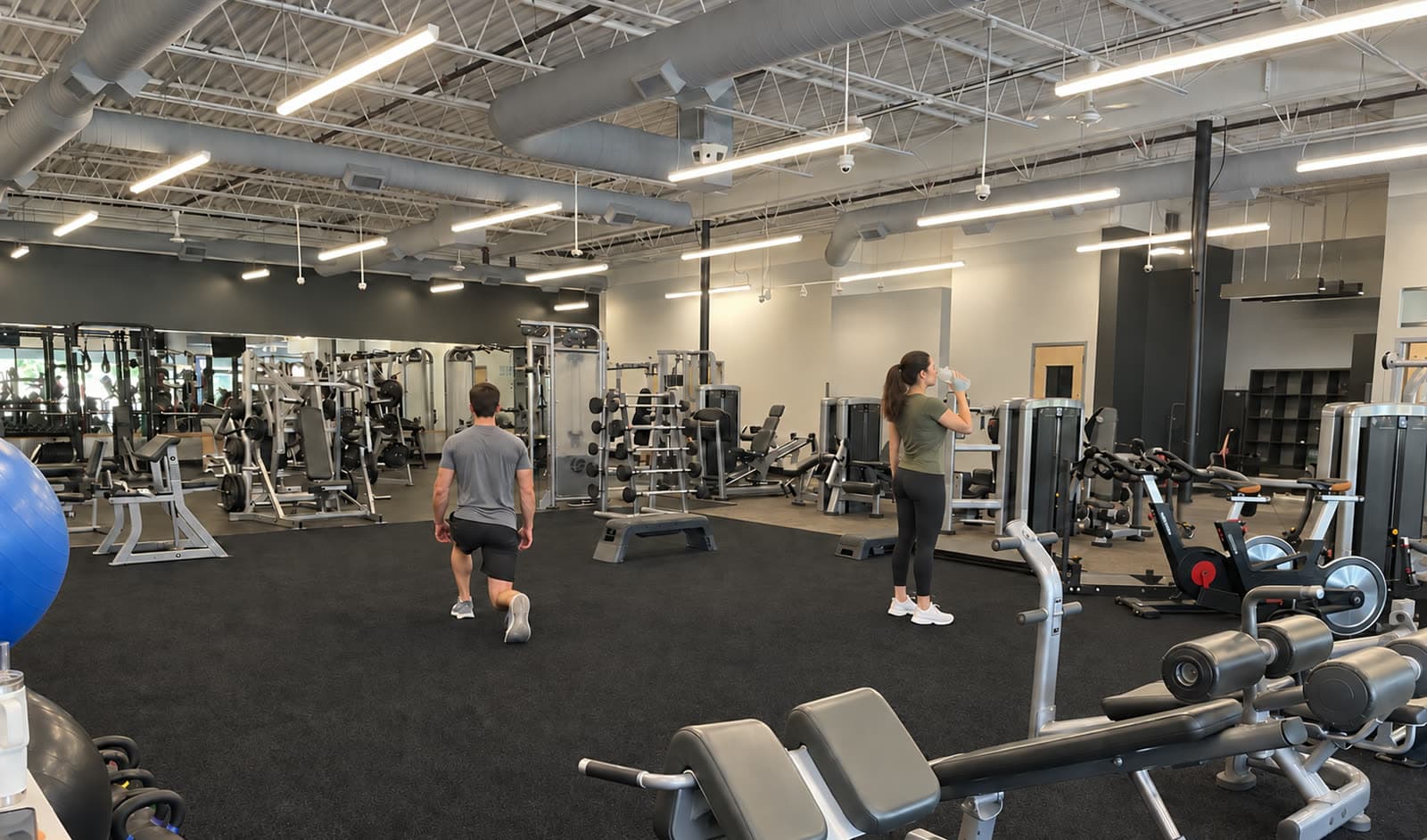 A chain gym floor with weight machines, a cable station and a dumbbell rack